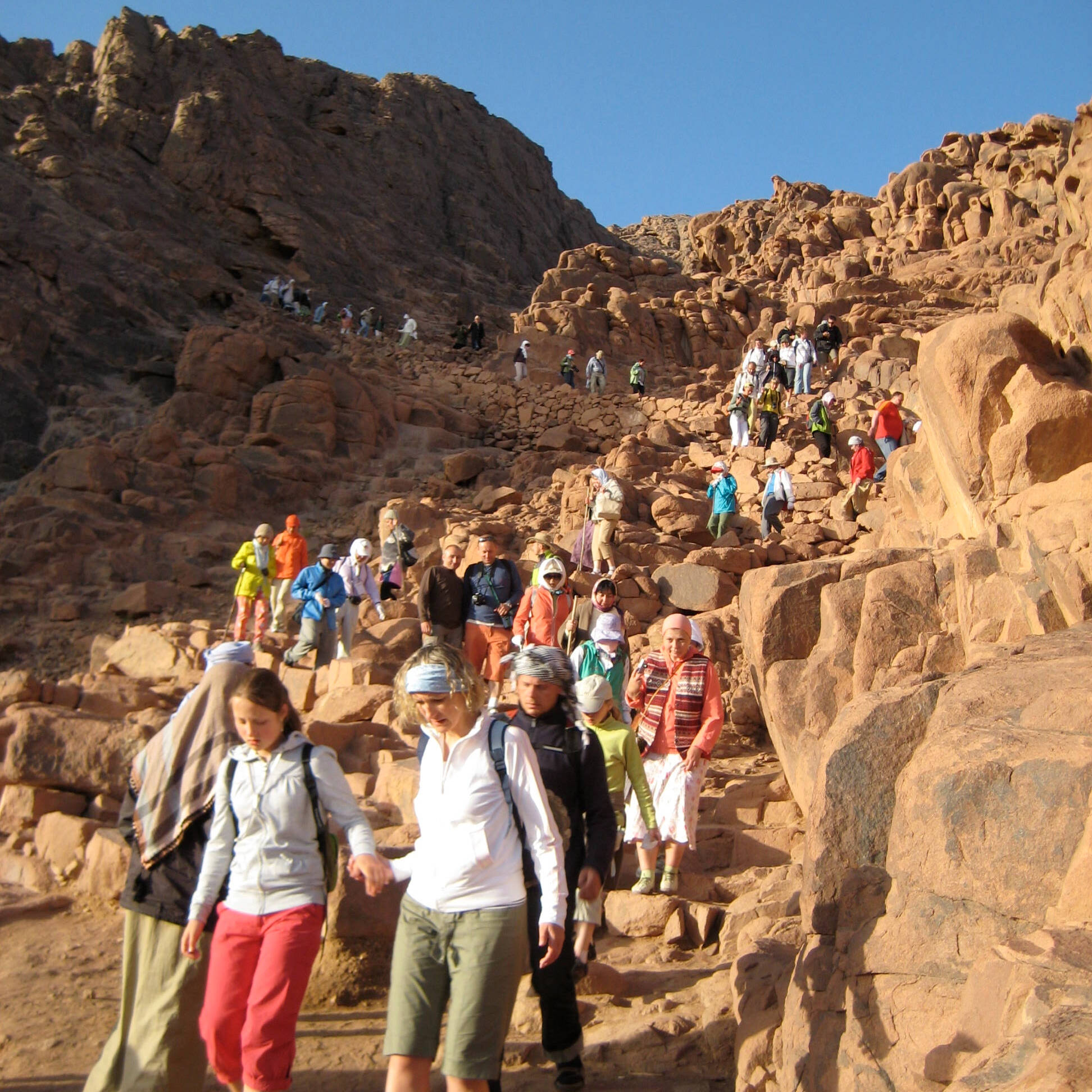 People Hiking Down a Steep Rocky Path